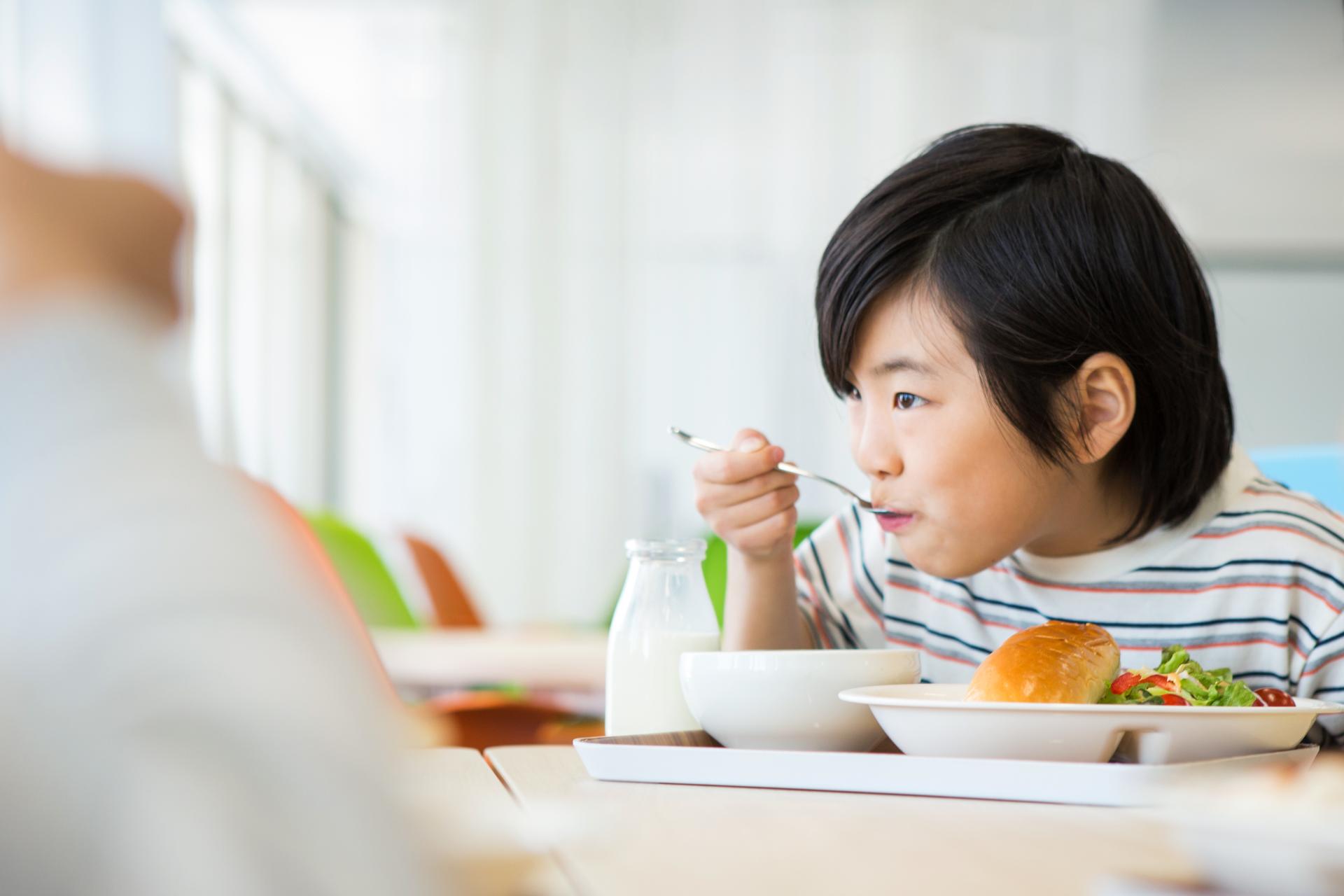 こどもが給食を食べている画像